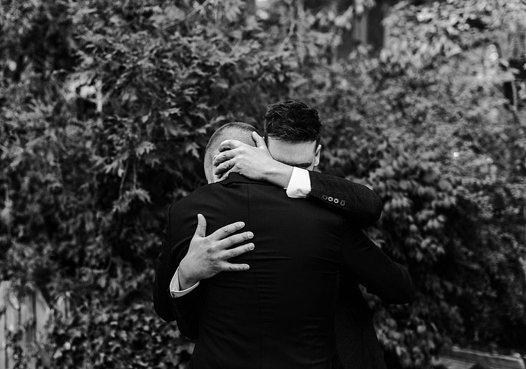 Black and white photo of two twin brothers embracing in a deep hug