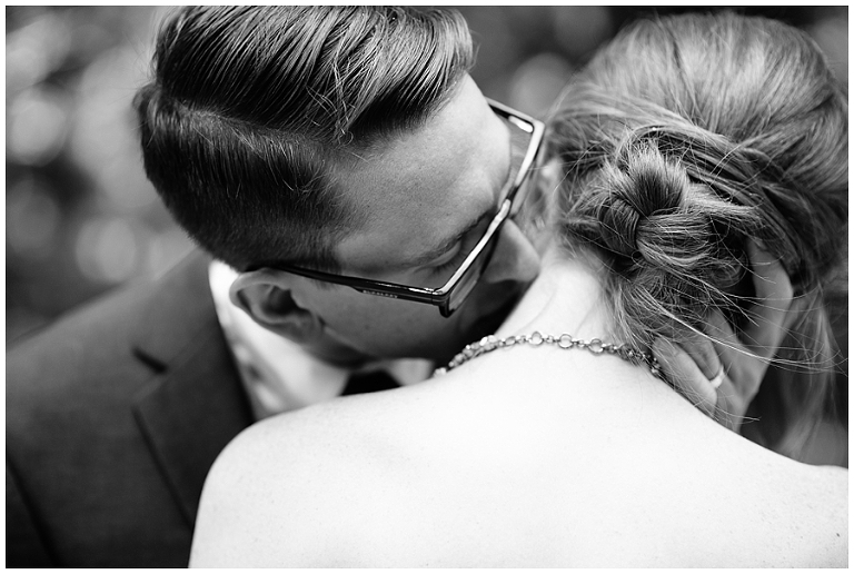 Groom kisses bride's neck in a B&W photo