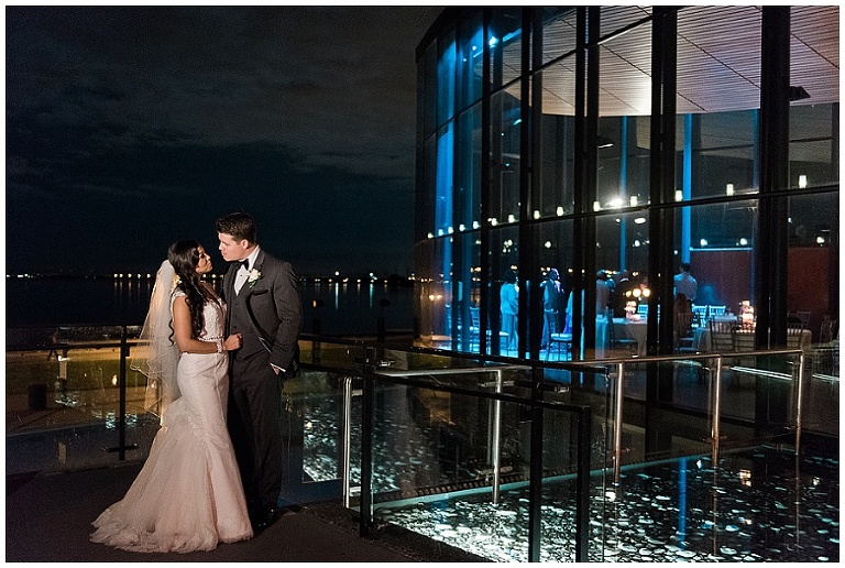 Couple standing outside of Spencer's at the Waterfront at night time, looking at each other