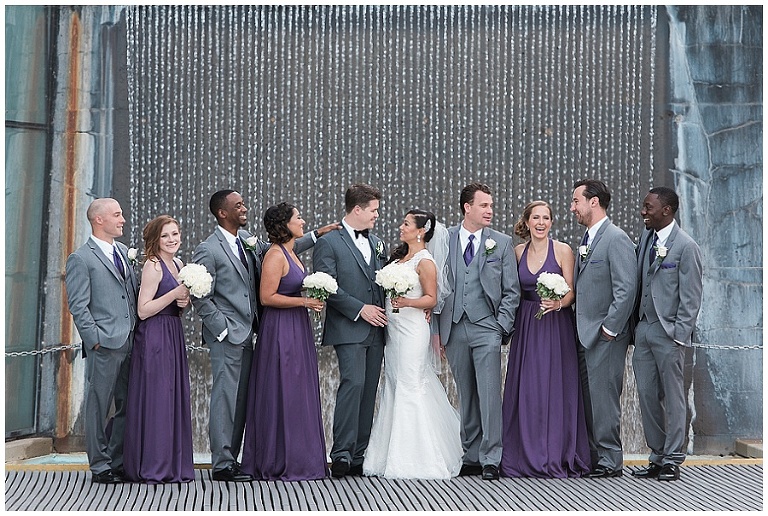 10 person wedding party standing in front of waterfall at Spencer's at the Waterfront wedding venue