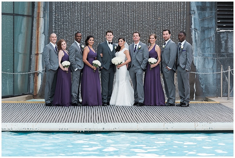 10 person wedding party standing in front of waterfall at outdoor wedding venue in the summer