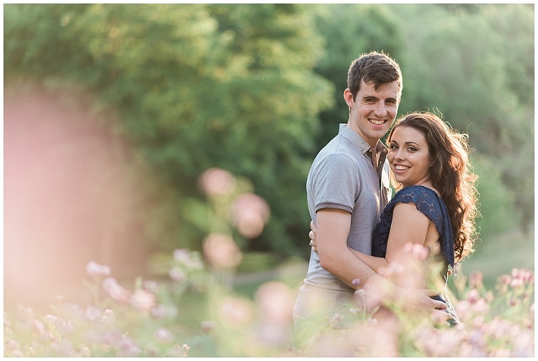 Engaged couple in love with golden sun hitting them perfectly in a patch of wildflowers