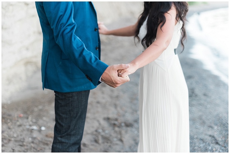 Couples holds hands during engagement session on beach
