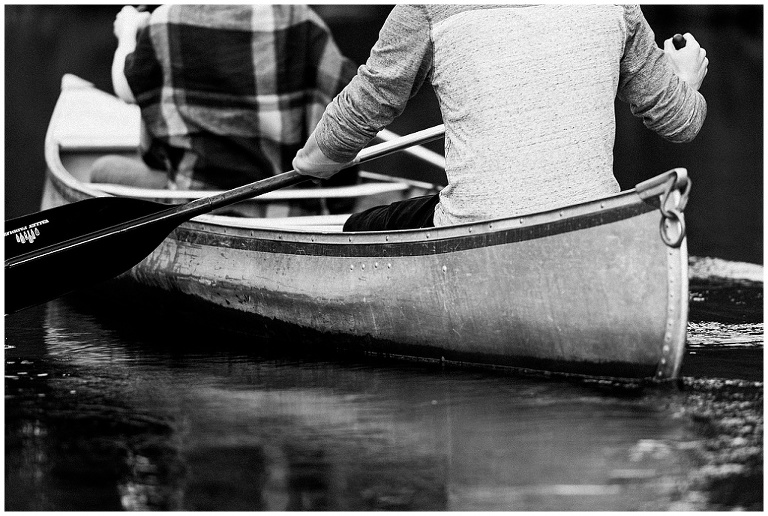 Black and white photo close up of back of canoe while paddling