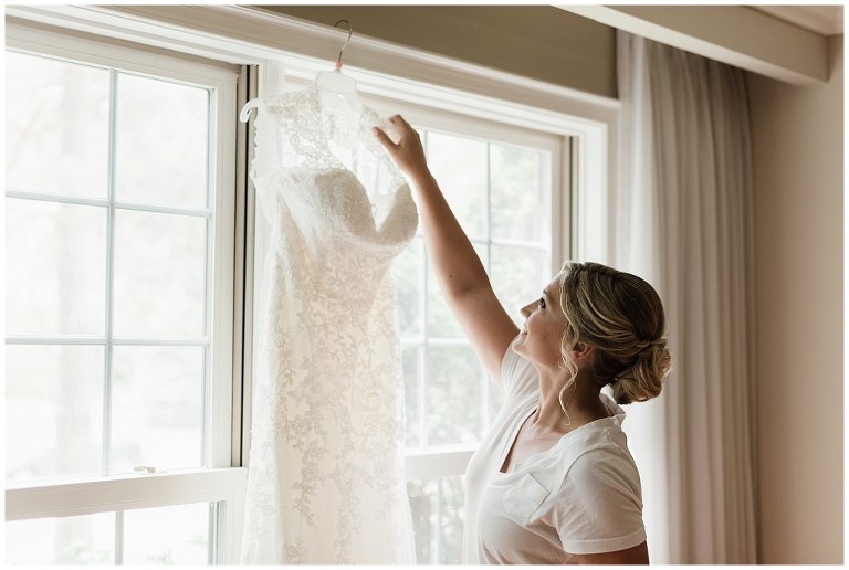 Bride grabbing the hanger with her wedding dress on the day of her wedding