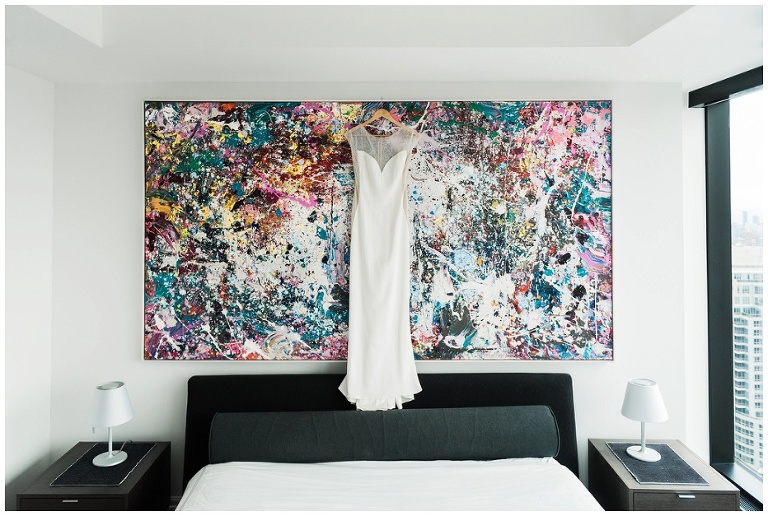 Modern wedding dress hanging from a piece of colourful splattered art in Toronto at Four Seasons Hotel Private Residences