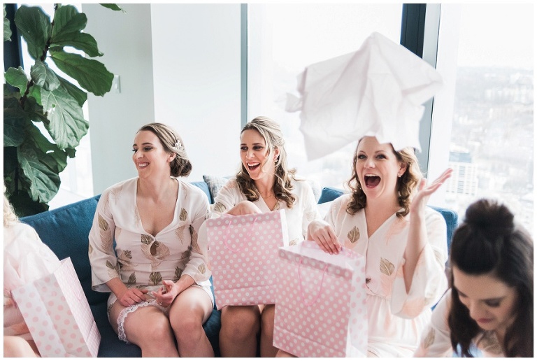 Bridesmaids opening their pink gift bags from Toronto bride and throwing the tissue paper in the air at Four Seasons Hotel wedding photos