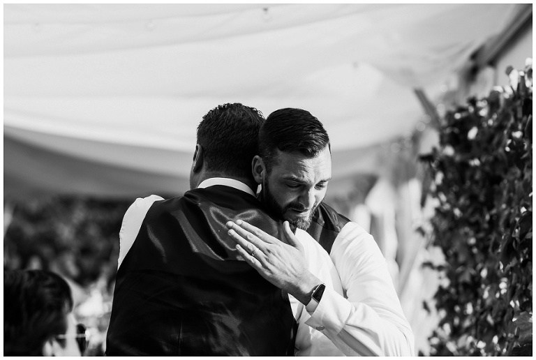 Groom hugging groomsman and almost crying at Kurtz Orchard wedding
