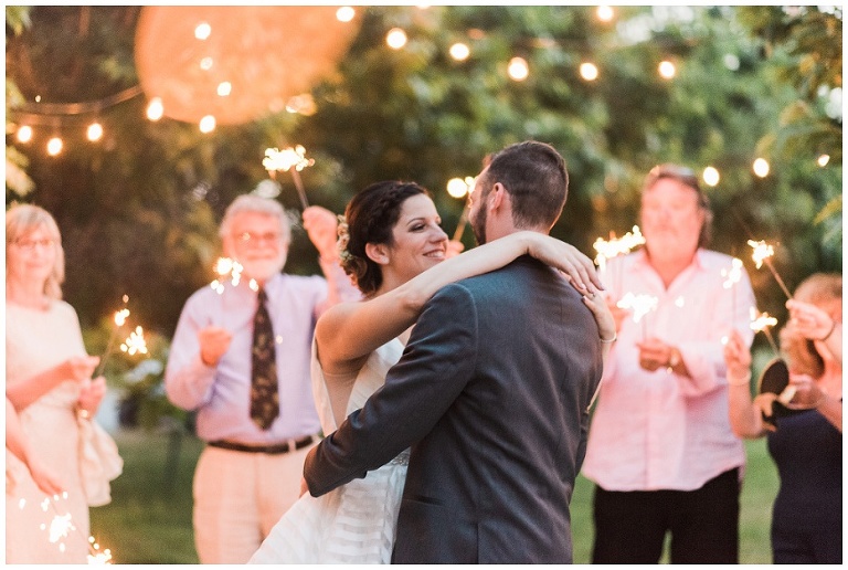 Bride and groom dancing at dusk with guests holding sparklers in background at Kurtz Orchard wedding