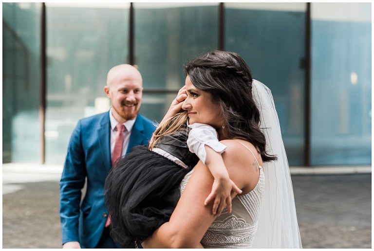 Bride hugging daughter after emotional first look at city hall before ceremony