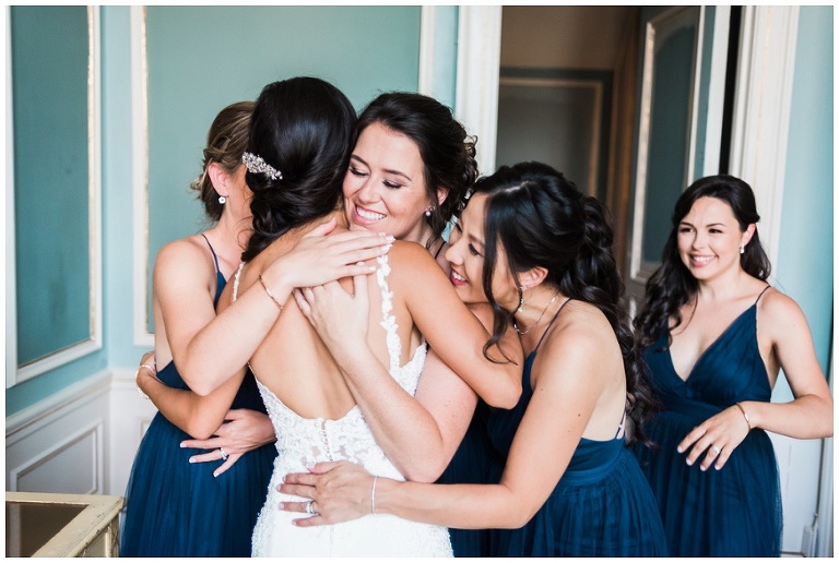 Bridesmaid's hugging bride with big smiles on their faces after first look