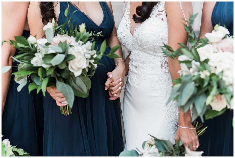Close up of bride holding sisters hands framed by their bouquets
