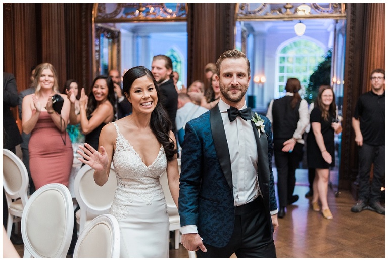 Bride and groom entering into wedding reception at Casa Loma with big smiles on their faces