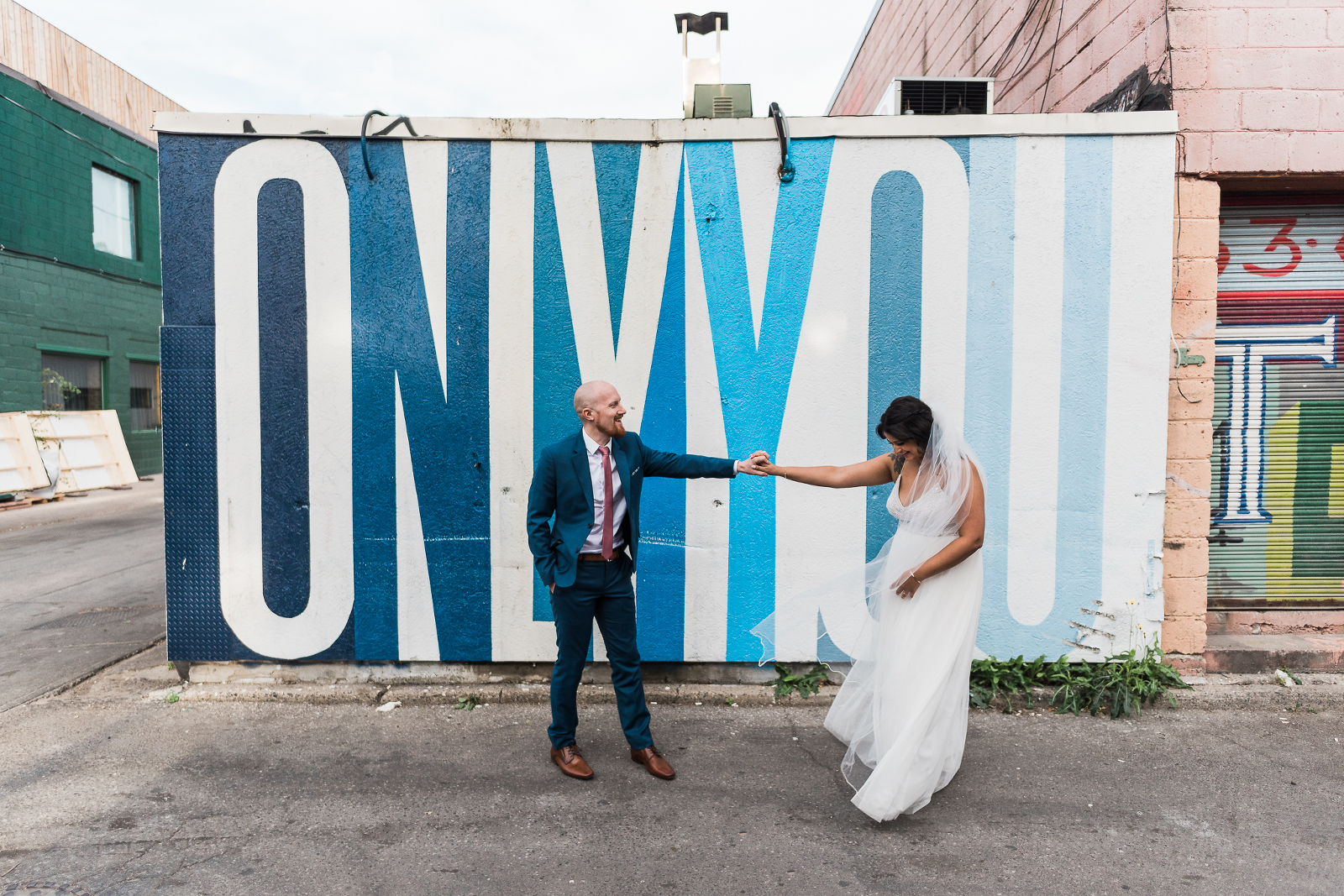Bride and groom dancing in front of Ben Johnston graffiti in downtown Toronto on their wedding day