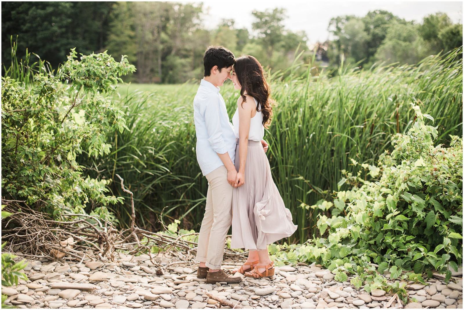 An asian couple embracing each other in front of the tall bright green reeds of a marsh