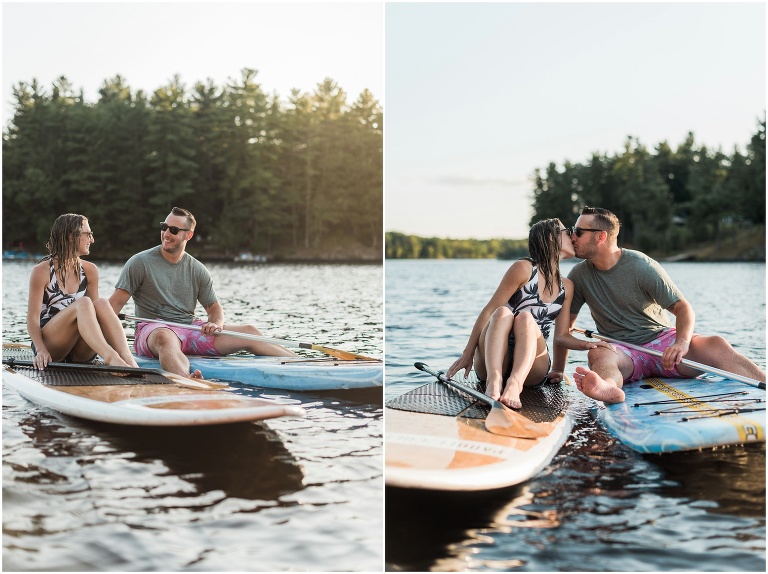 Man and woman sitting on their paddle boards, leaning across to kiss each other in the water
