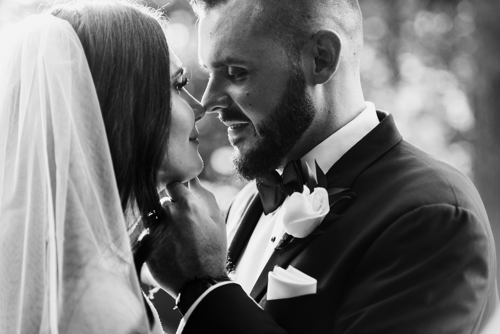 Black and white photo of groom touching bride's face to kiss at Ancaster Mill wedding