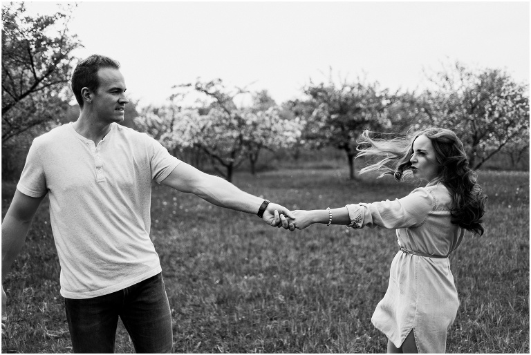 Couple holding hands and swinging each other around during their spring time engagement session