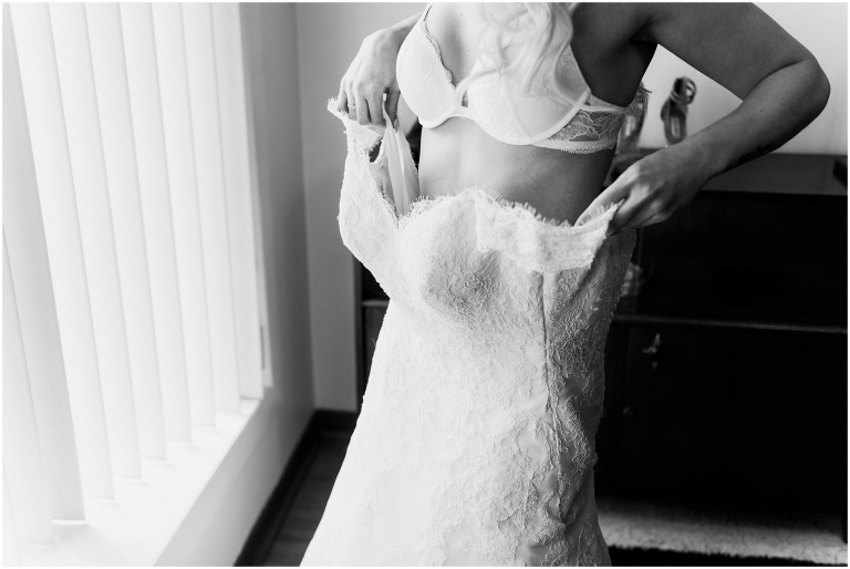 Bride slips on her wedding dress in the living room