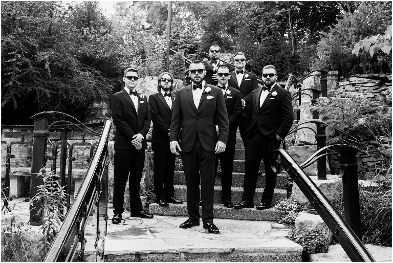 Black and white photo of groom with his groomsmen standing on the stairs at the Ancaster Mill on his wedding day