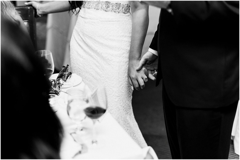 black and white photo of bride and groom holding hands during their wedding reception at Ancaster Mill