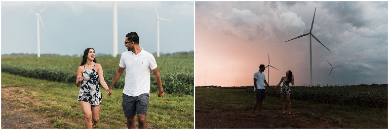 Couple holds hands and runs together in field in front of windmills in Dunnville Ontario for the engagement photos