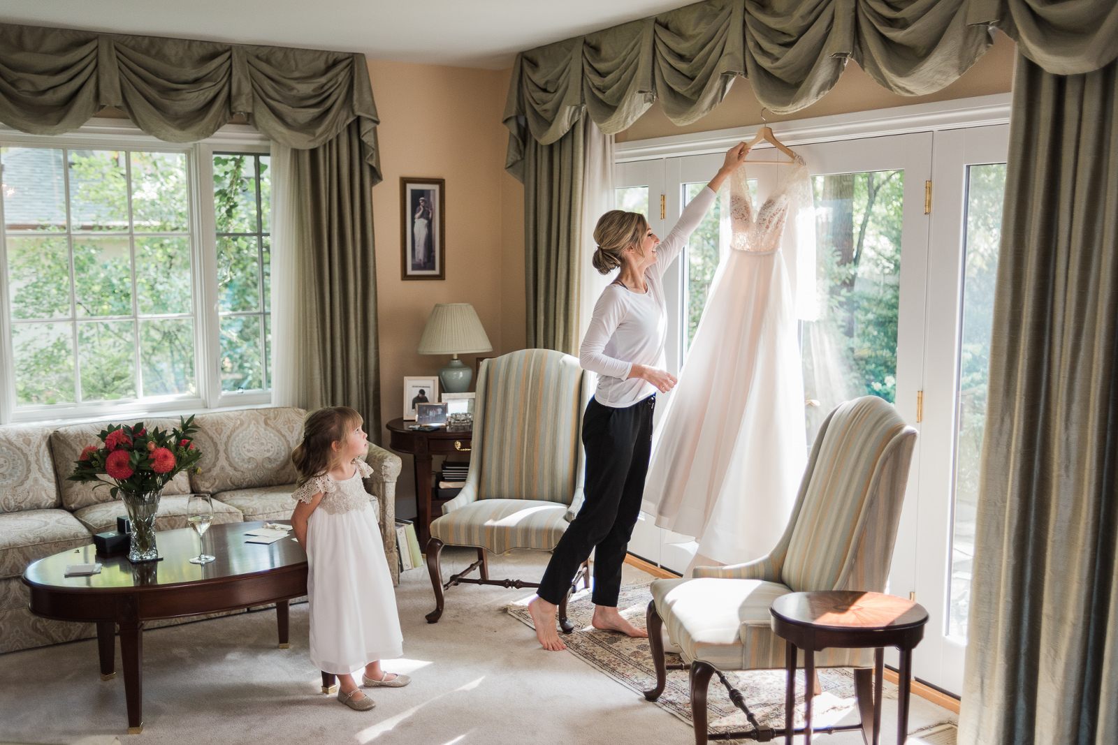 Bride reaching for her dress in the living room while her niece watches