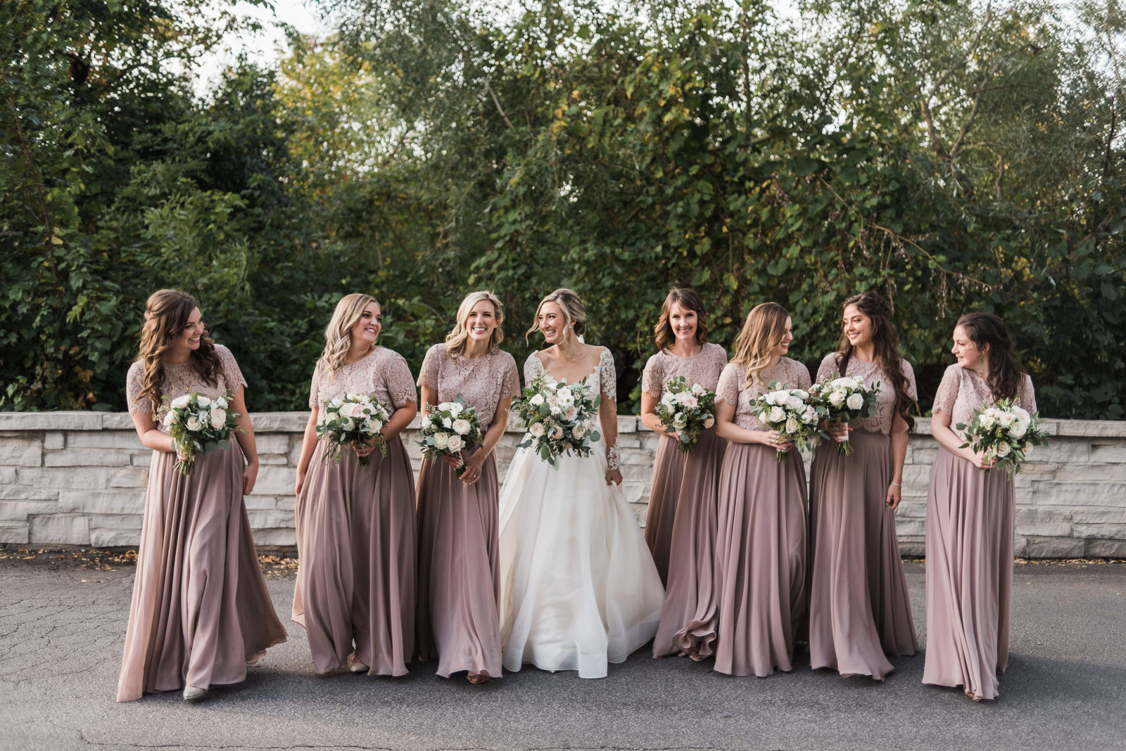 Bride and her bridesmaids walk together in their dusty pink dresses