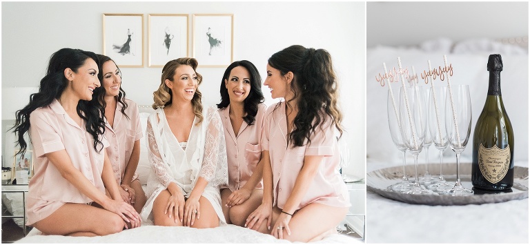 Bridesmaids sitting together on bed in pink pajamas beside bride in her white lace robe
