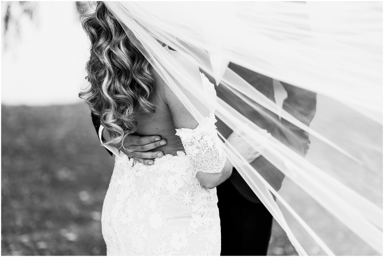 Close up black and white photo of grooms hand on the small of brides lower back
