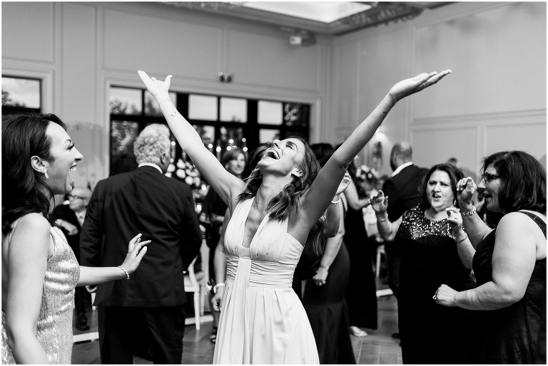 Black and white photo of guest raising their hands in the air in joy during live music by The Truly Band