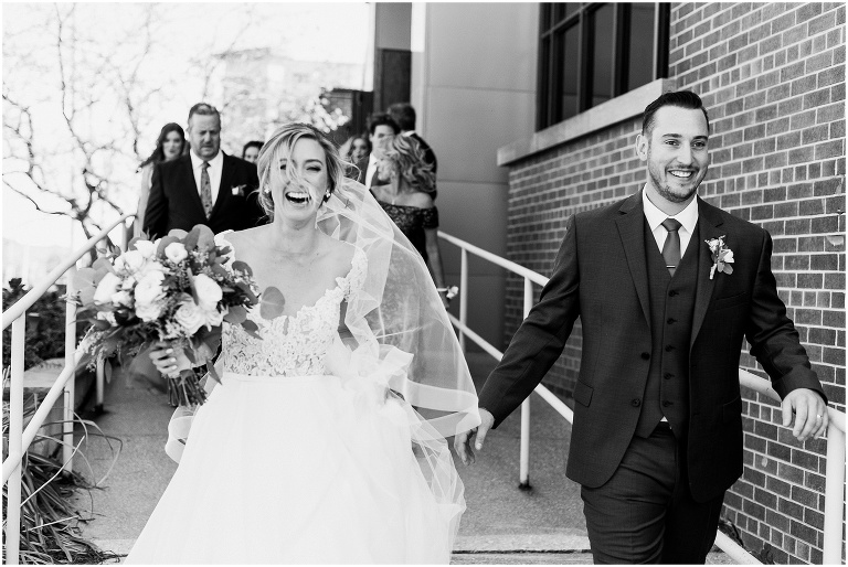 Candid moment of bride and groom walking in black and white