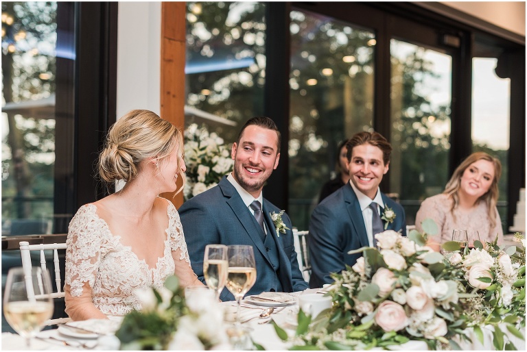Groom smiling joyfully at bride during the speeches at their elegant Credit Valley Golf and Country Club wedding 
