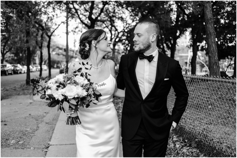 Black and white photo of bride and groom walking down street together