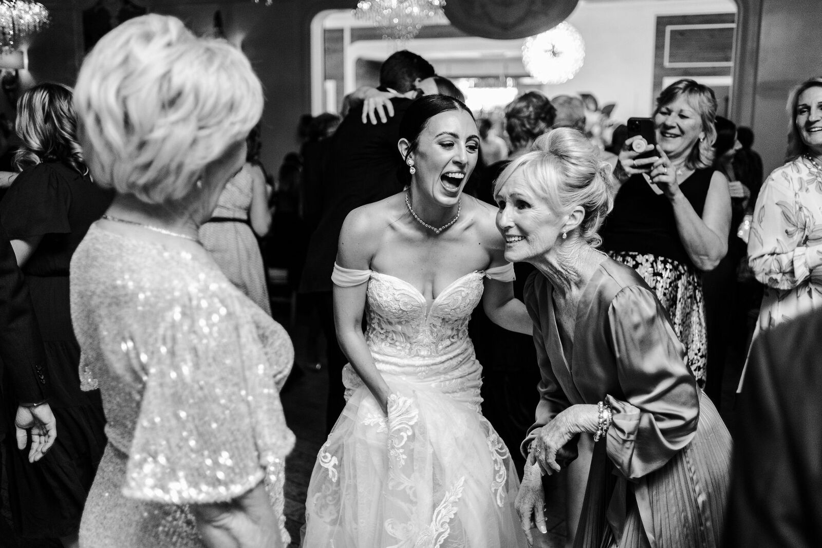 Black and white photo of the bride on the dance floor with an older guest & they are both very happy and having fun