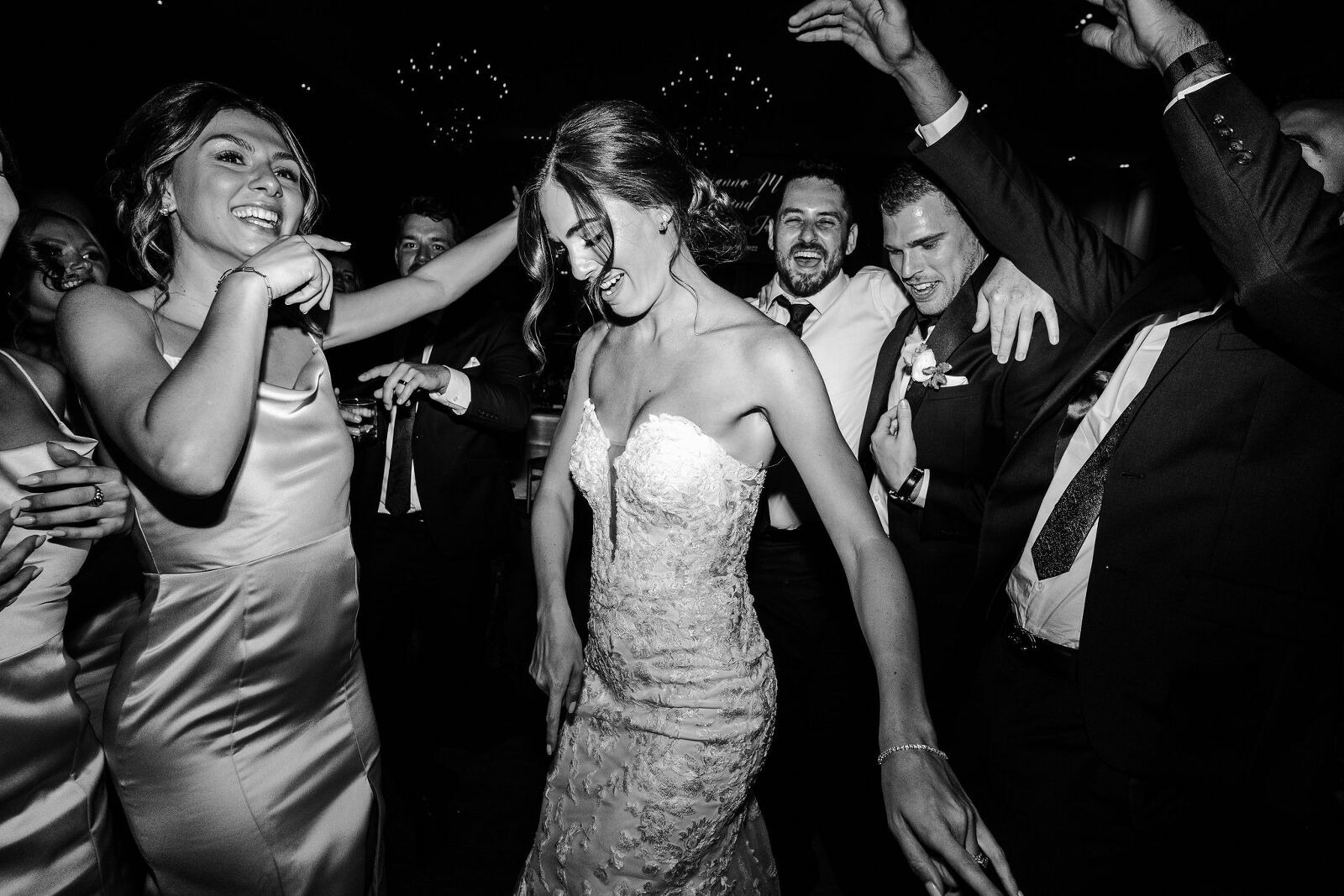 black and white photo of bride and wedding party dancing on the dance floor at wedding