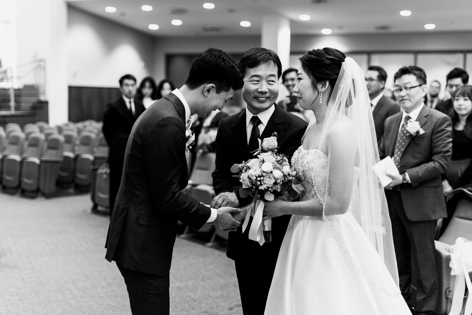 Bride's korean fother looking lovingly at her as he gives her hand away to the groom