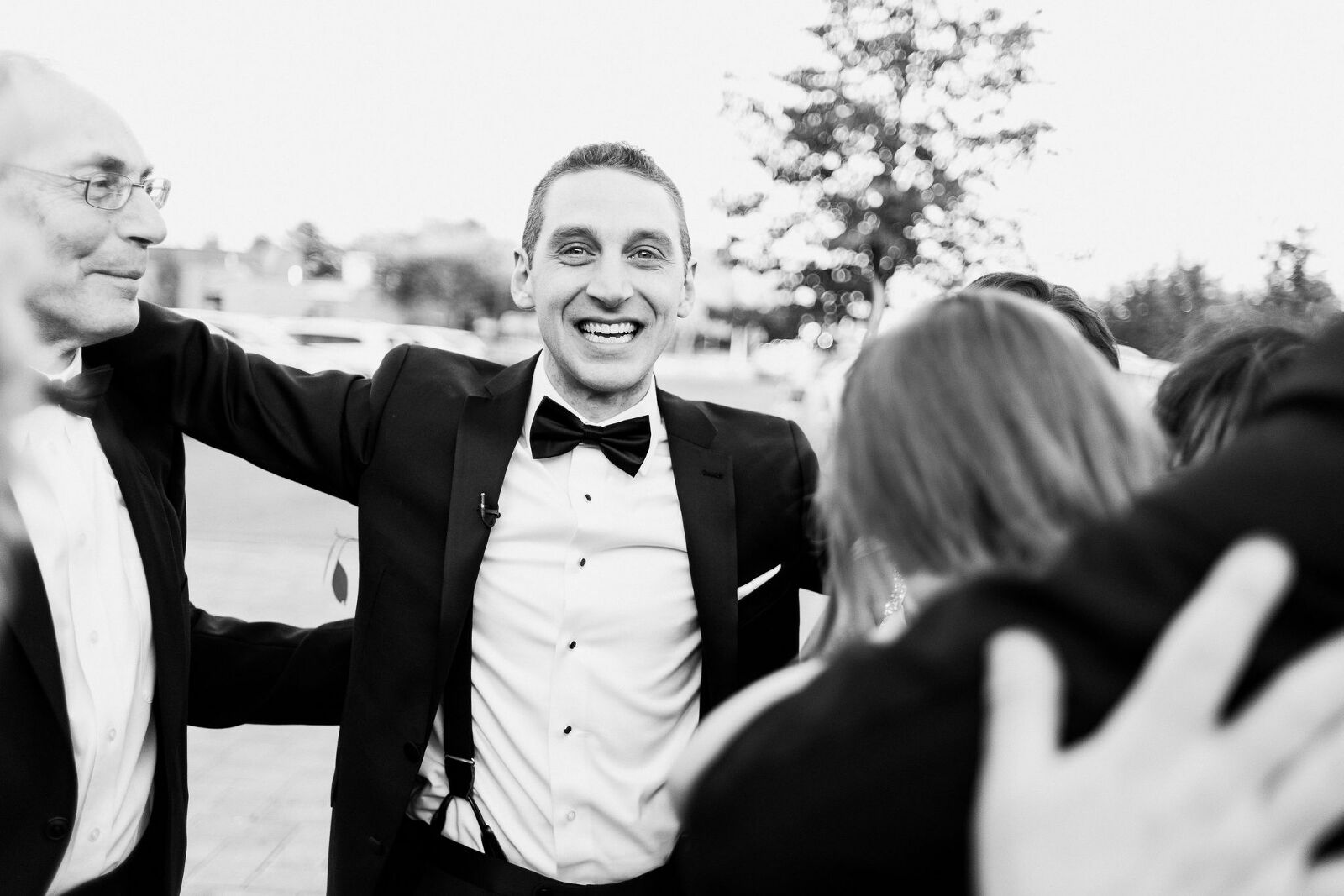 Groom is ecstatic and smiling directly into the camera as he greets his family after getting married