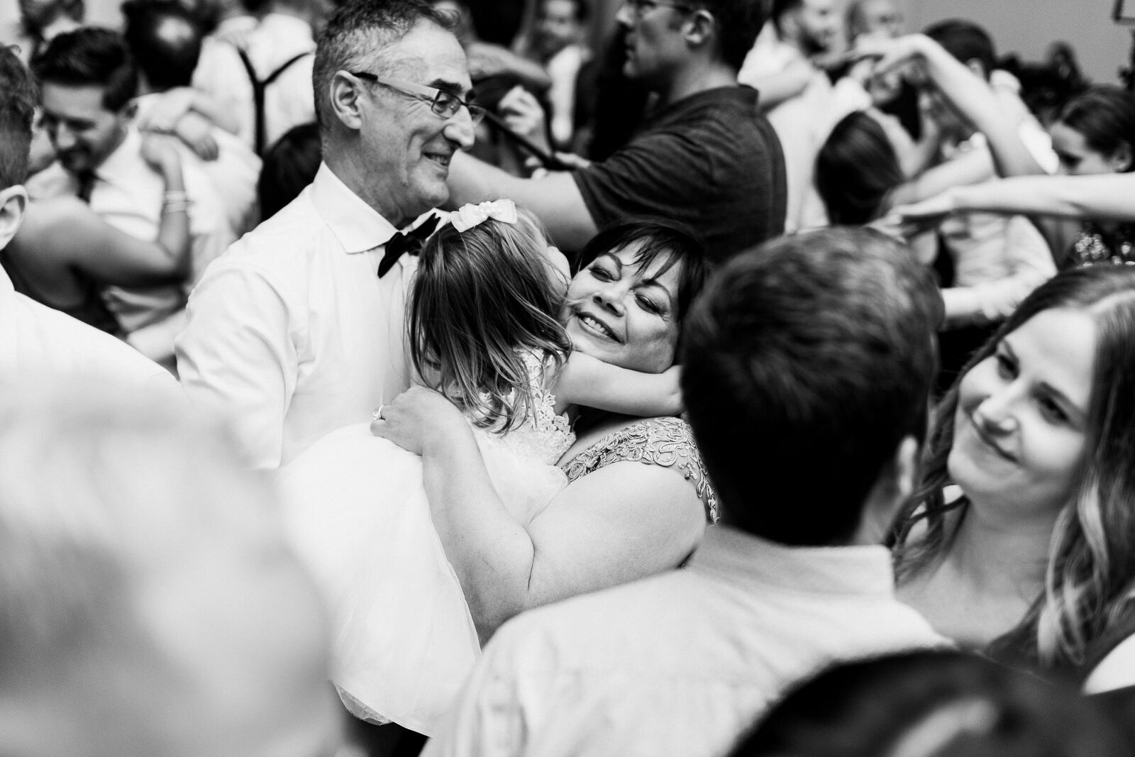 Grandmother hugs granddaughter in the middle of the dance floor surrounded by people