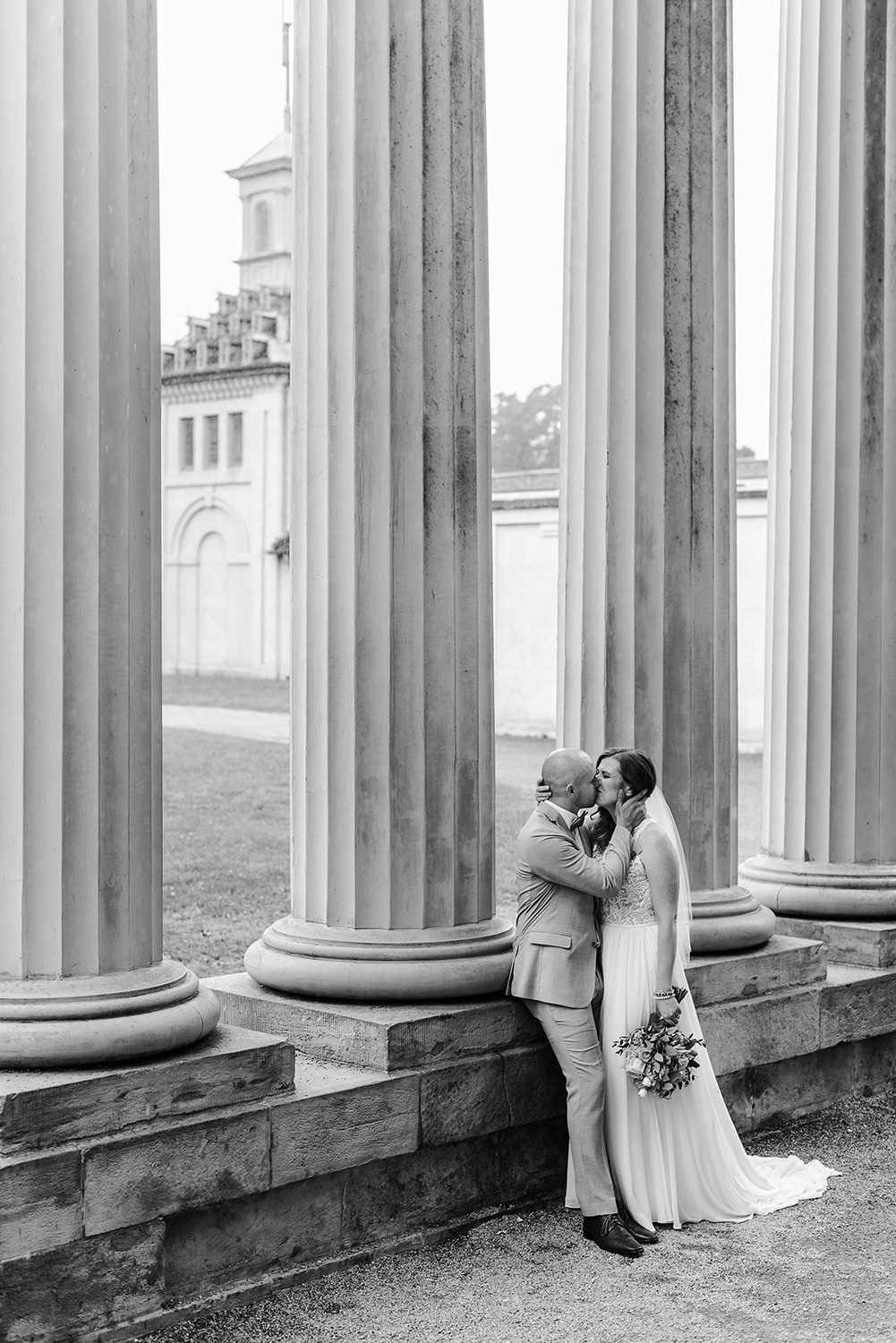 Bride and groom kiss each other under massive columns at Dundurn Castle