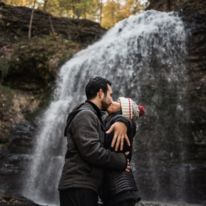 Couples poses in front of waterall after getting engaged