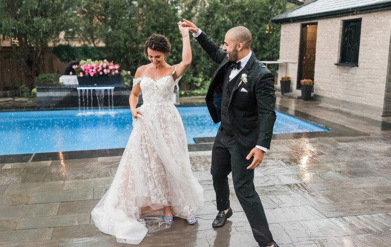 A couple dancing in the rain on their wedding day